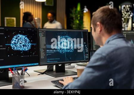 System administrator in tech startup office automating repetitive tasks using AI scripts on PC. IT expert using artificial intelligence application on computer to speed up feature implementation Stock Photo