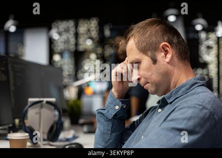 Close up of dejected man in startup office bummed after noticing error in code while doing quality assurance. Glum IT worker frowning, concerned by glitches in programming language Stock Photo