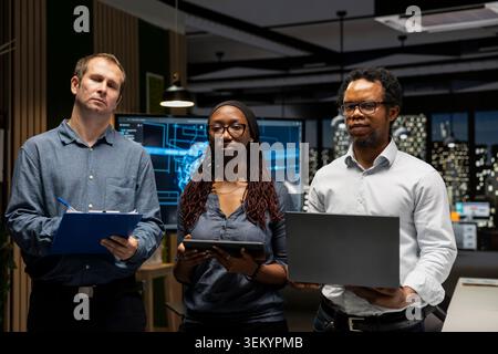 Portrait of engineers in office automating repetitive tasks using AI scripts on devices. Teamworking IT experts using artificial intelligence to speed up feature implementation Stock Photo