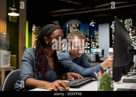 Manager and intern cooperating in AI focused startup, designing, coding and debugging applications. Team leader and trainee at PC desk doing brainstorming, testing code, doing quality assurance Stock Photo