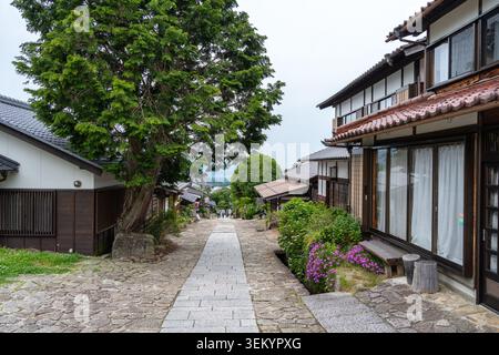 Stone path through the charming historic village of Magome on the scenic Nakasendo trail, surrounded by wooden houses and lush gardens Stock Photo