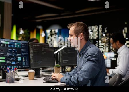 Jolly worker in Silicon Valley startup office pleased with help offered by AI assistant doing tasks. Delighted engineer satisfied by performance of high tech artificial intelligence LLM models Stock Photo