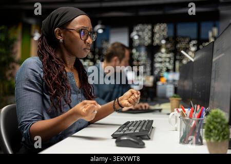 Programmer in tech startup office optimizing code for performance and scalability, doing quality assurance. IT professional at work looking at programming language on computer monitor Stock Photo