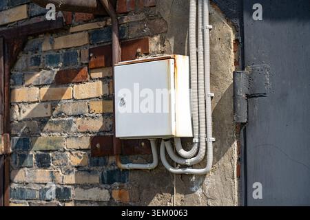 Industrial Electrical Box Mounted on a Rustic Brick Wall with Exposed Wiring and Weathered Details Reflecting Urban Infrastructure Stock Photo