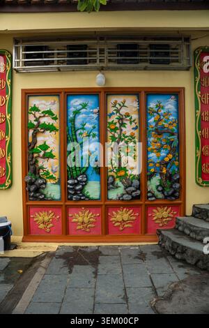 A colorful decorative relief panel on the facade of a Vietnamese building, divided into four vertical sections depicting traditional nature scenes — p Stock Photo