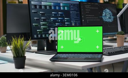 Green screen mockup laptop in office used to automate app development tasks with machine learning. Chroma key notebook in empty startup workplace leverages AI to accelerate feature implementation Stock Photo