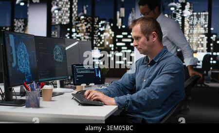 Tech startup IT expert developing artificial intelligence algorithms in high rise office late at night. System administrator debugging neural network brain models on screens Stock Photo