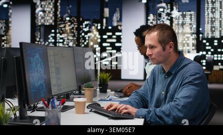Engineer in company workplace drinking coffee, doing artificial intelligence tech quality assurance. Worker in office enjoying caffeinated beverage, writing AI script with programming languages Stock Photo