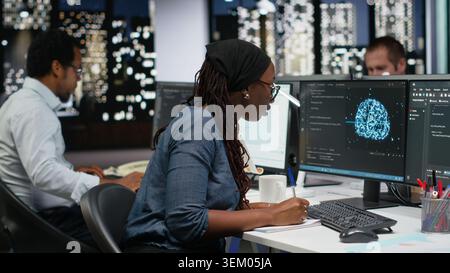 Programmer taking notes at desk in Silicon Valley company office, developing apps. IT expert using machine learning to do coding, writing on notepad, debugging applications to resolve issues Stock Photo