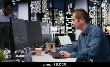 Programmer typing complex code on computer, developing machine learning models to automate business tasks in workspace. Developer writing programming language scripts on PC Stock Photo