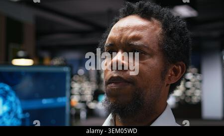 Close up of technician in office developing complex machine learning algorithms simulating human brain thought processes. African american man deploys AI tools, performing quality assurance Stock Photo