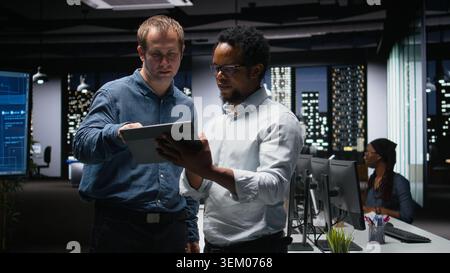 Engineers developing artificial intelligence algorithms in modern high rise office. IT experts debug applications while visualizing 3D neural network brain models on glowing screens Stock Photo