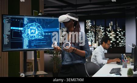 Technician in office using VR headset gear to fix bugs in artificial intelligence system. Worker troubleshooting neural network errors with virtual reality equipment in tech agency workplace Stock Photo