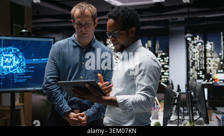 Programmers in office analyzing machine learning algorithms to prevent AI model errors. Colleagues reviewing code logic to improve artificial intelligence prediction accuracy Stock Photo
