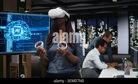 Developer in office using VR headset gear to analyze machine learning algorithms. IT expert uses virtual reality equipment to improve artificial intelligence prediction accuracy Stock Photo