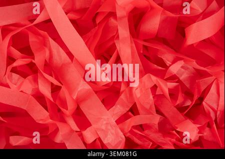 Red paper strips are arranged in a messy way on a flat surface, showing their texture and color. They can be used in art or for events. Stock Photo