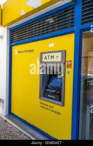 Lagoa Algarve Portugal, An automated teller machine from Banco Montepio is mounted on a vibrant yellow wall with blue framing, offering convenient fin Stock Photo