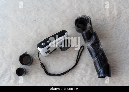 White analog film camera with black strap and unrolled 35mm film roll with canisters on white fluffy surface flat lay. Concept of analog photography Stock Photo