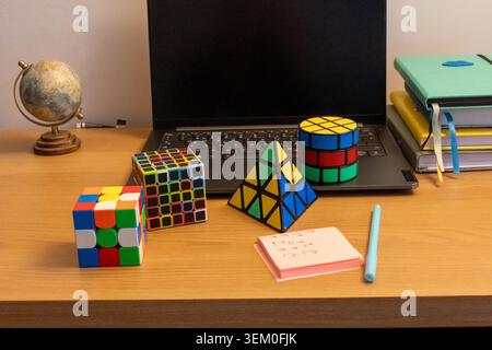 Collection of colorful 3D logic puzzles of various shapes including cube, pyramid and cylinder arranged on wooden desk. Logical thinking, brain Stock Photo