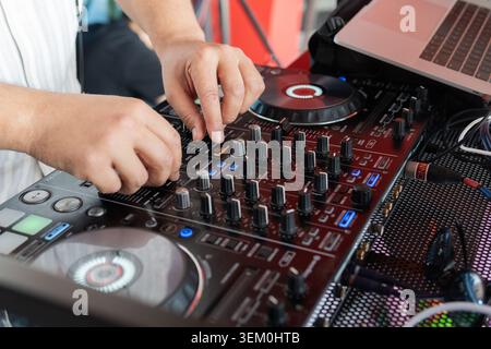 DJ mixing music on professional sound equipment at a live event, close-up of hands on mixer and controls. Electronic concept Stock Photo