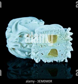 White marshmallow with vanilla filling on black background showing soft airy texture and cross section with reflection. Stock Photo
