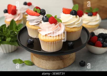 Yummy cupcakes with fresh berries and mint on grey table, closeup Stock Photo