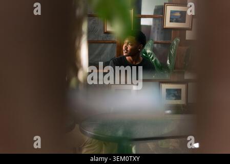 Young black man contemplating, looking away with thoughtful expression indoors Stock Photo