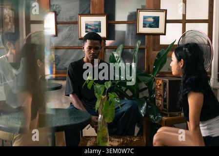 Young man sitting in cafe looking distant from woman reflecting on relationships Stock Photo