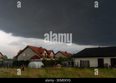 Dramatic storm front moving over quiet suburban homes under dark rain clouds. Concept of severe weather, changing climate, approaching rainfall Stock Photo