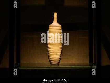 Elegant Textured Ceramic Vase Displayed on a Glass Shelf Under Warm Spotlight Stock Photo