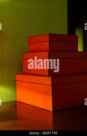 Three Red Luxury Leather Gift Boxes Stacked on a Wooden Surface in Warm Lighting Stock Photo