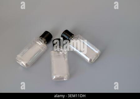Three clear plastic bottles with black caps on a gray background Stock Photo