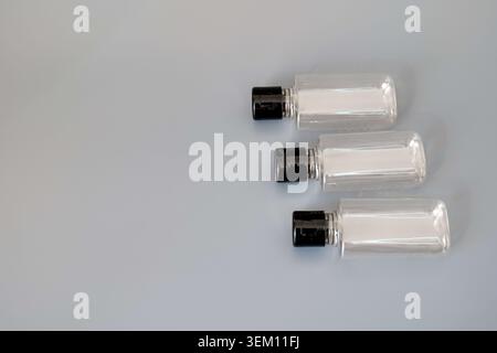 Three clear plastic bottles with black caps on a gray background Stock Photo