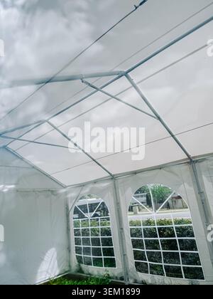 Riga, Latvia - June 4, 2026: Bright white marquee tent interior featuring a transparent roof structure with dramatic cloudy sky visible above. Ideal f Stock Photo