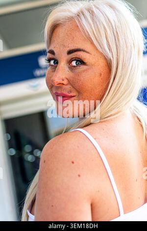 Confident blonde woman with freckles posing outdoors Stock Photo