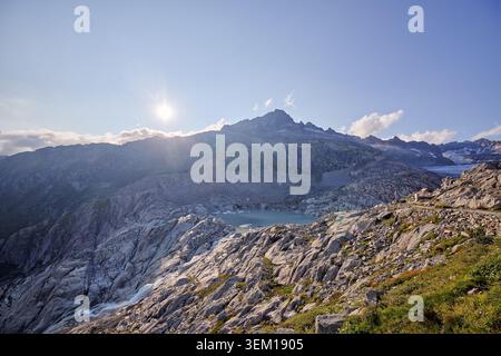 A rugged mountain range is lit by low sunlight under a dramatic cloudy sky. Stock Photo