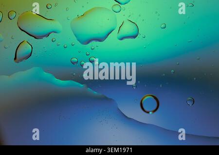 Macro shot of fluid dynamics showing floating oil drops over vibrant, colorful light leaks Stock Photo
