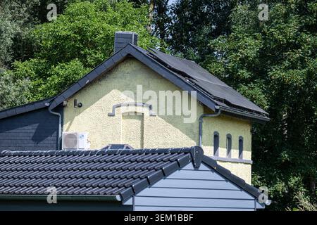 A house with a yellow façade and black slate roof is partly hidden by trees and vegetation in the countryside near Lessines. Lessines, Belgium 27 MAY Stock Photo