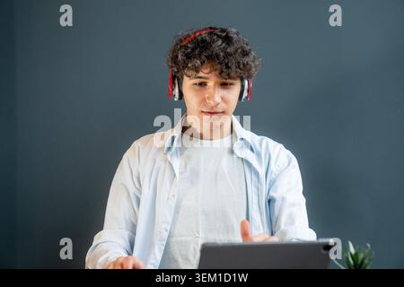 Young learner concentrating on a tablet during an online lesson or digital training session. Suitable for educational technology, e-learning, remote s Stock Photo