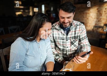 Happy friends laughing watching content on smartphone in cafe Stock Photo