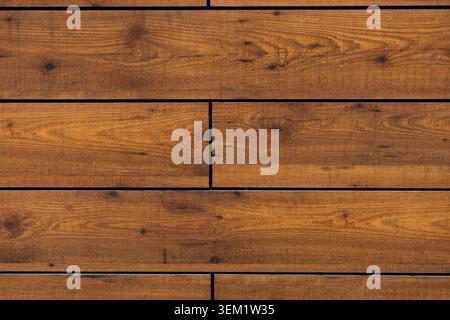 Full frame view of horizontal brown wooden planks arranged in a brickwork pattern with detailed grain and knots. Stock Photo
