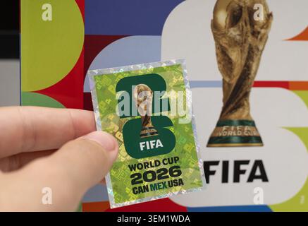 hand holding an official holographic Panini sticker for the 2026 FIFA World Cup, with the collector's album blurred in the background Stock Photo