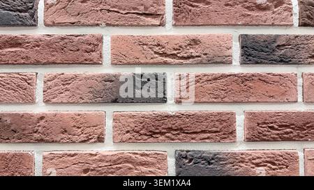 Close-up of red decorative brick wall texture with rough surface and light mortar joints. Stock Photo