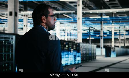 Writing code, tablet closeup and engineer in data center compiling software patches to fix bugs. Running programming script, device application and IT professional in server farm, camera A Stock Photo