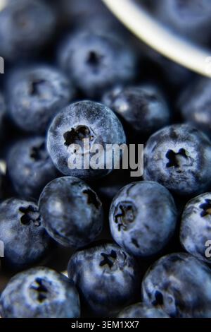 Full frame vertical macro shot of ripe blueberries. One single berry is in sharp focus while the surrounding ones are blurred due to shallow depth of Stock Photo