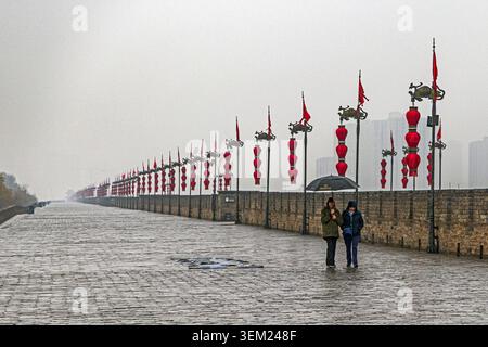 Tourists with umbrellas on the walkway around the Xi'an City Wall, a well-preserved ancient fortification in China Stock Photo