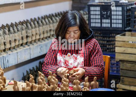 Chinese craftswoman sculpting miniature Terracotta Army replica figures in a workshop at the Arts and Ceramics Exhibition Centre in Xi'an, China. Stock Photo