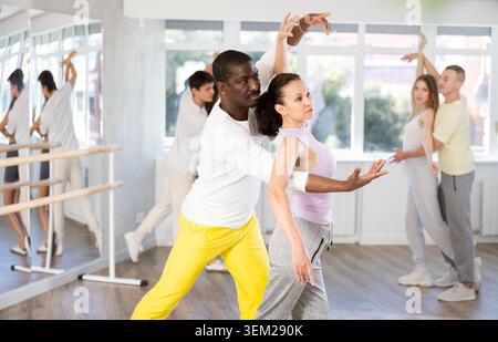 Group of men and women in sportswear learning to dance latin dances in dance studio Stock Photo