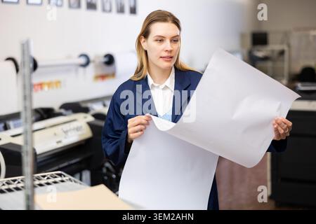 Print worker controlling printing process on modern offset machine in print shop Stock Photo