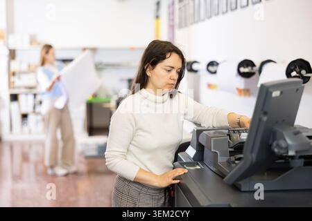Technician operator calibrating plotter machine, typing on computer keyboard Stock Photo